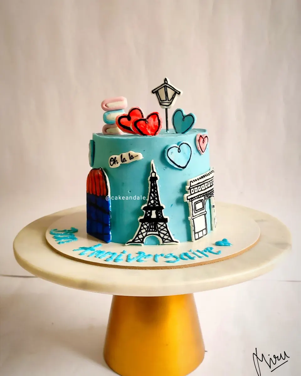 Sky blue anniversary cake with hand-painted Eiffel Tower, Arc de Triomphe, macarons and hearts