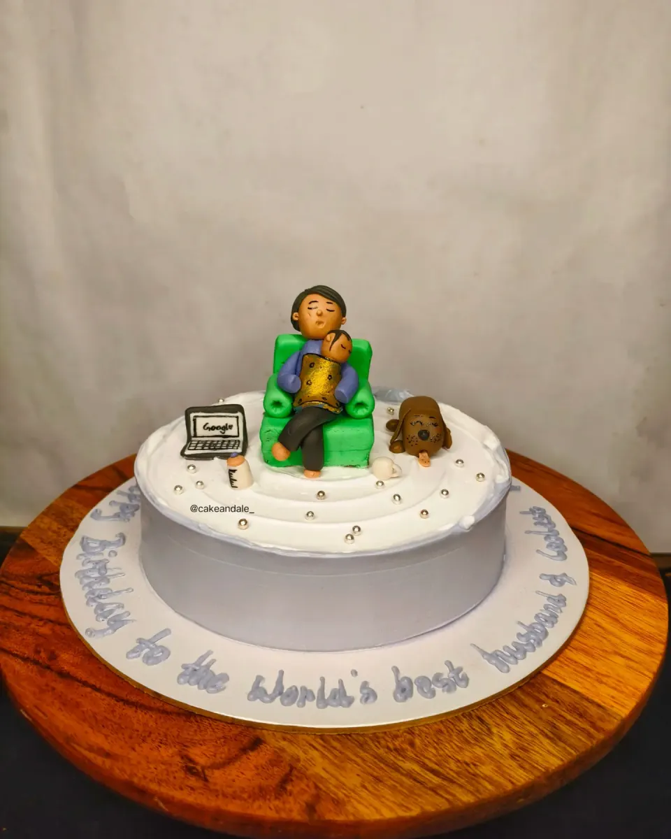 Side view of a white birthday cake with a fondant family napping in a green armchair
