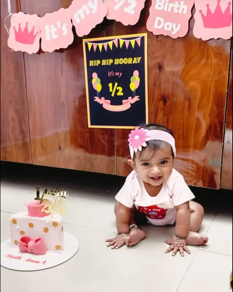 Smiling baby at her half birthday party next to her Cake and Ale half cake