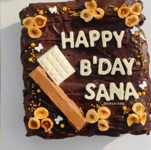 Chocolate brownie cake topped with hazelnuts, chocolate bars and "Happy B'day Sana"
